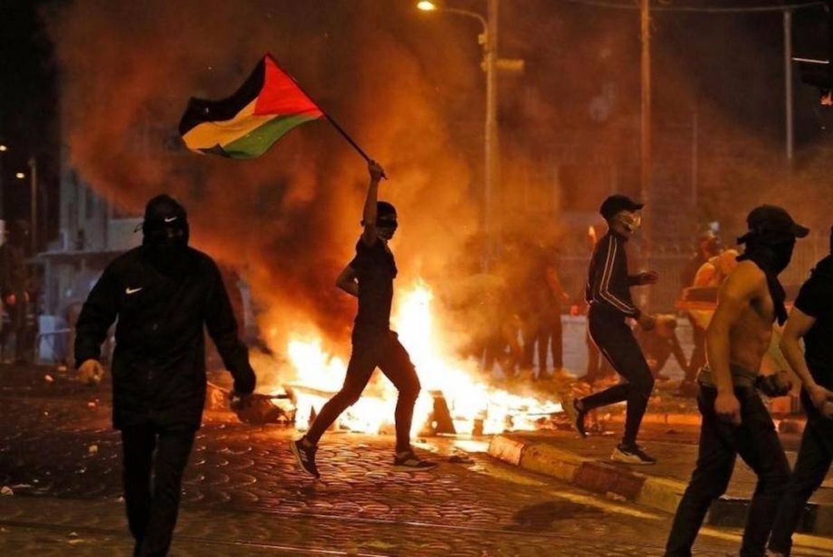 صورة متداولة على مواقع التواصل الإجتماعي لمتظاهر يرفع العلم الفلسطيني خلال احتجاجات أيار 2021
