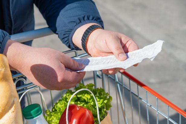 Shopper,Holding,And,Checking,Long,Supermarket,Receipt,Above,Cart,With | Shutterstock